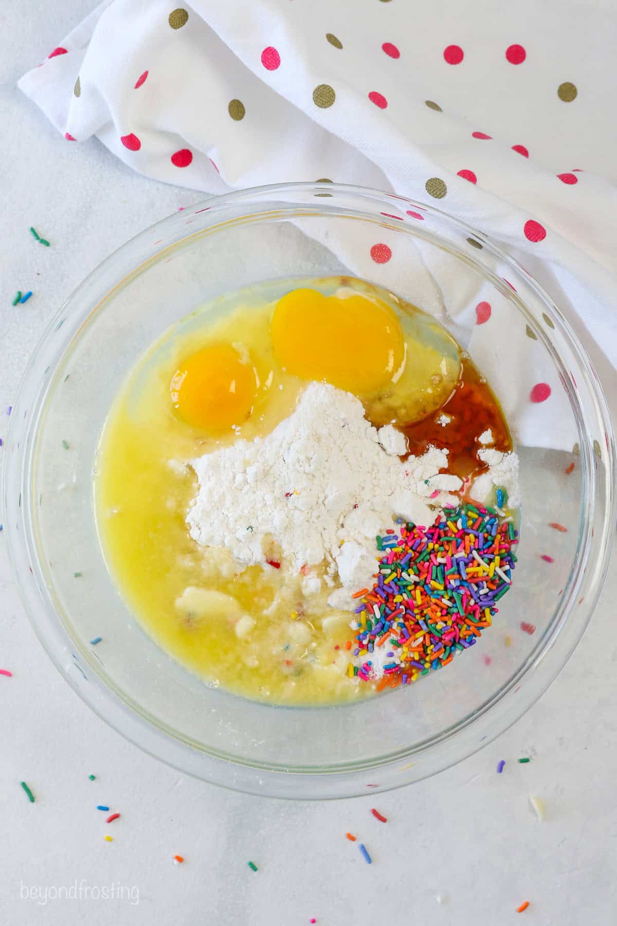 Funfetti cookie dough ingredients combined in a glass mixing bowl.