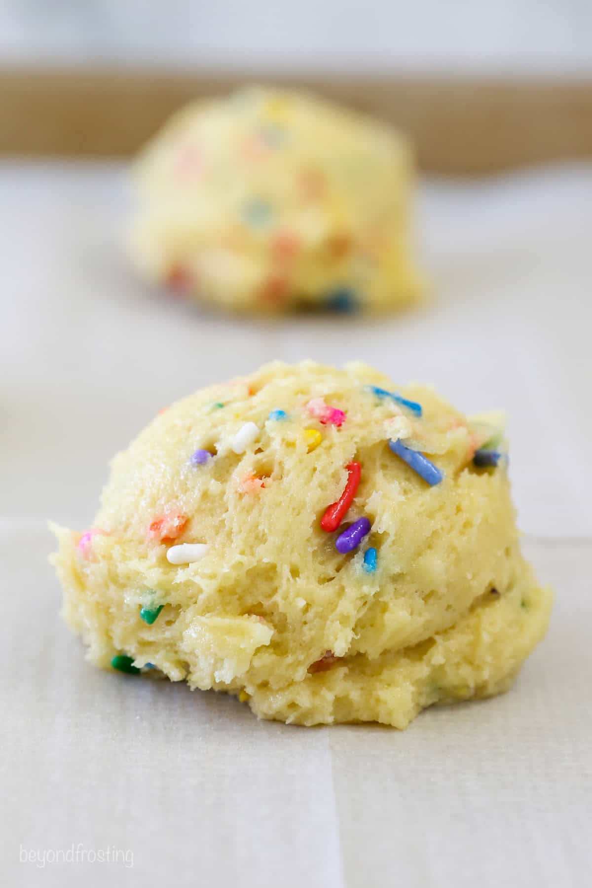 A scoop of funfetti cookie dough with a second scoop in the background.