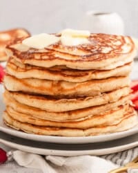 A stack of buttermilk pancakes topped with pats of butter on a plate.