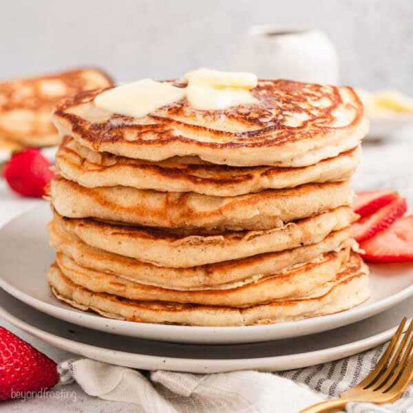 A stack of buttermilk pancakes topped with pats of butter on a plate.