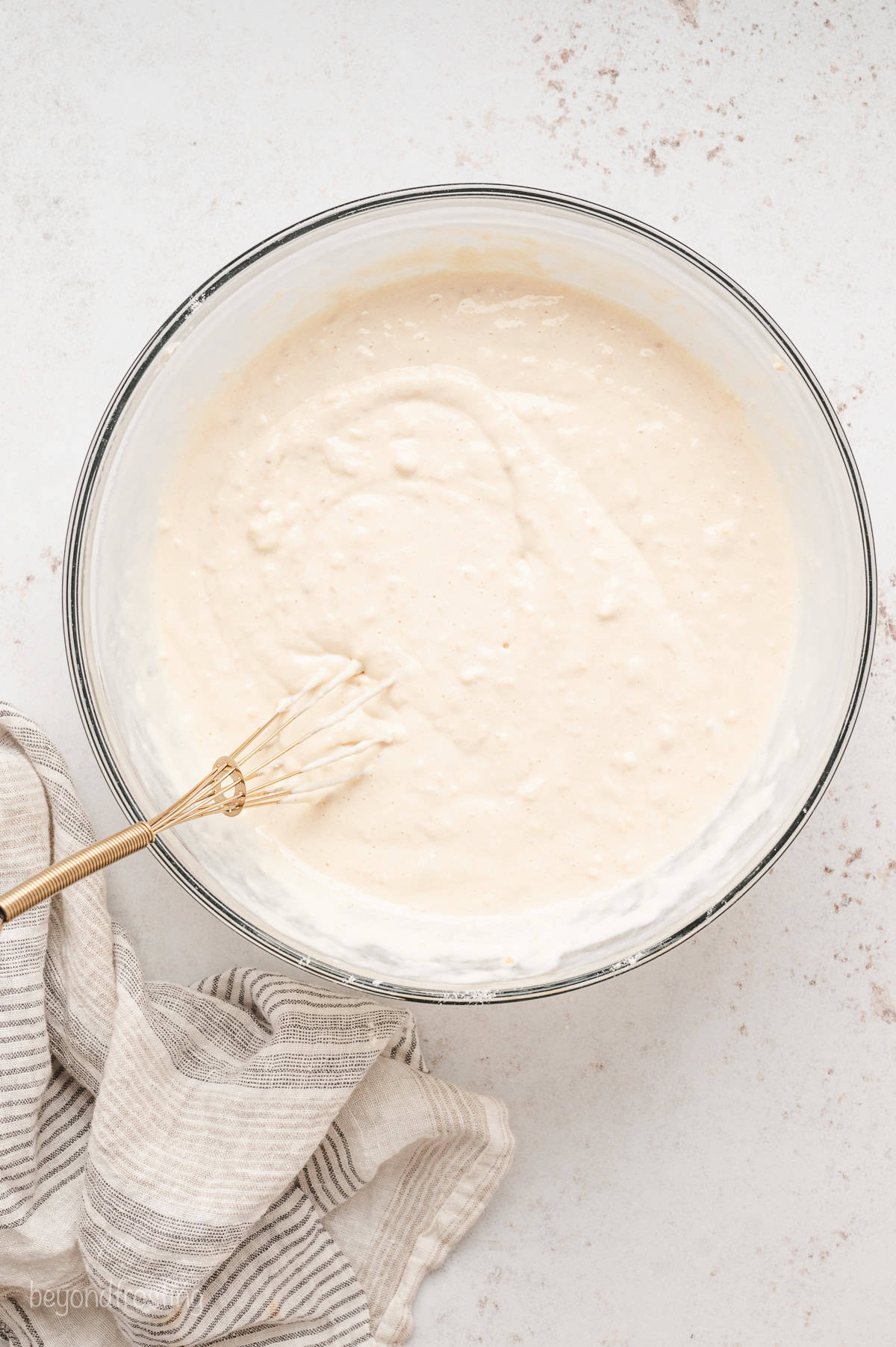 Buttermilk pancake batter in a large bowl with a wooden spoon.