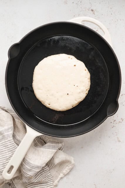 Buttermilk pancake batter cooking in a skillet.