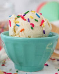 A teal bowl filled with ice cream and sprinkles