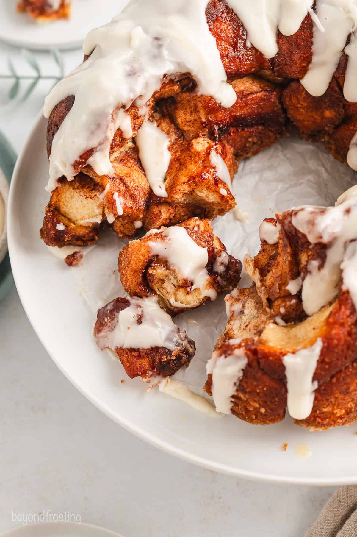 Overhead view of partially pulled-apart cinnamon roll monkey bread covered in vanilla icing.