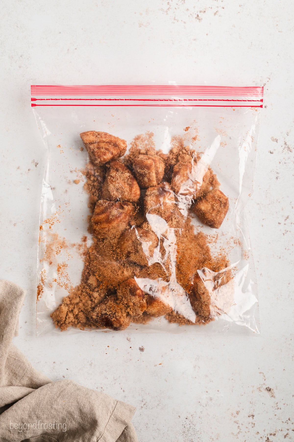 Cinnamon roll dough balls coated with cinnamon sugar inside a Ziploc bag.