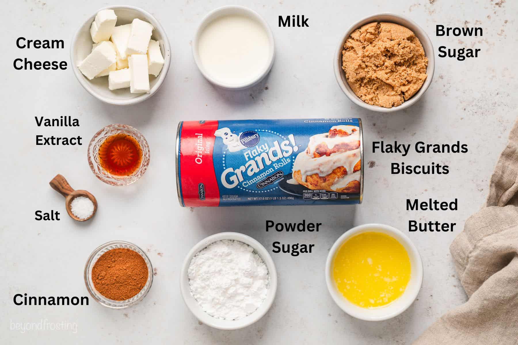 Ingredients for cinnamon roll monkey bread with text labels overlaying each ingredient.