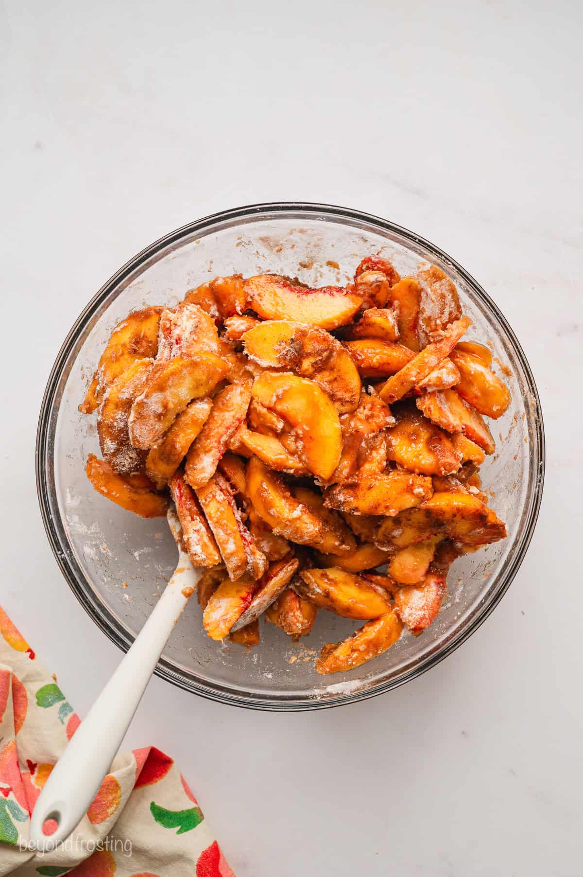 Peach pie filling in a glass bowl with a spatula.