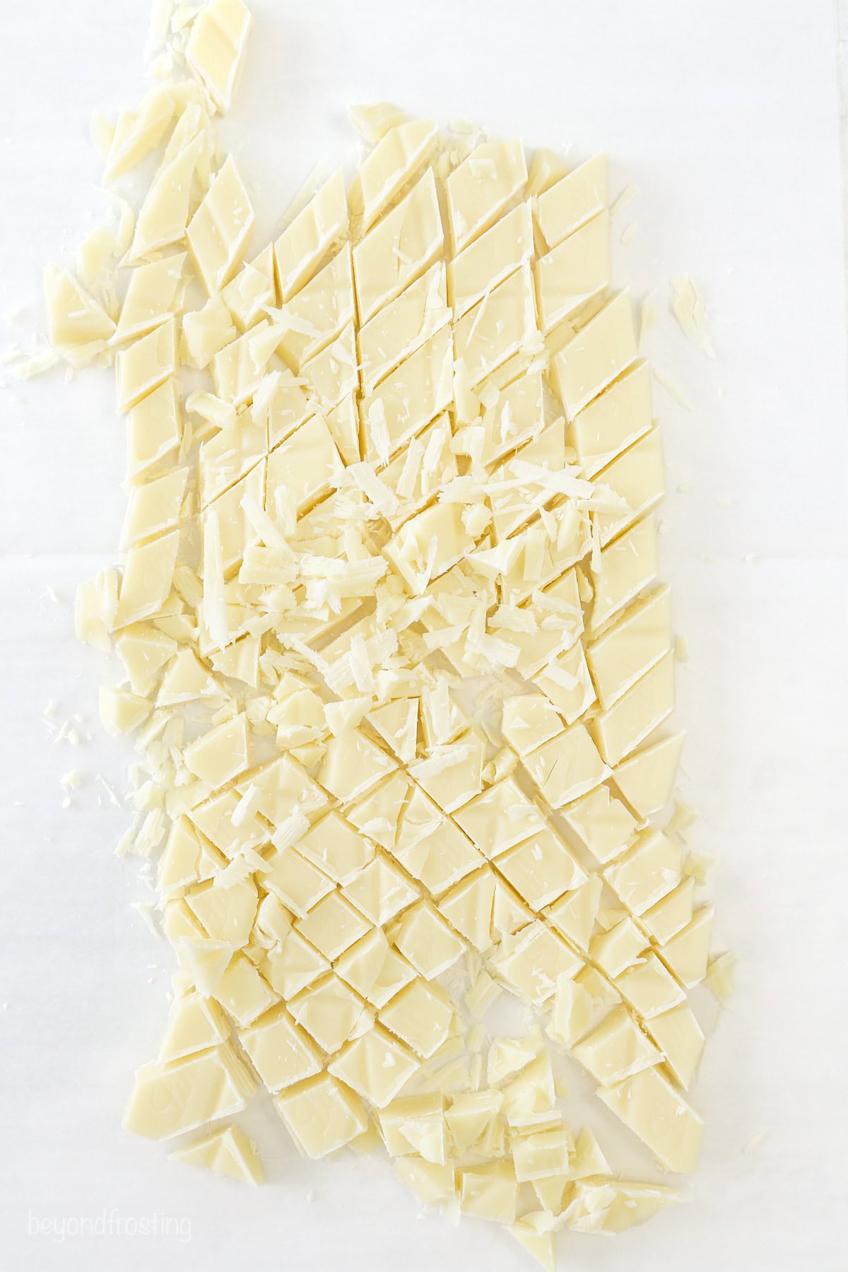 Overhead view of white chocolate bars chopped into smaller pieces on a white countertop.