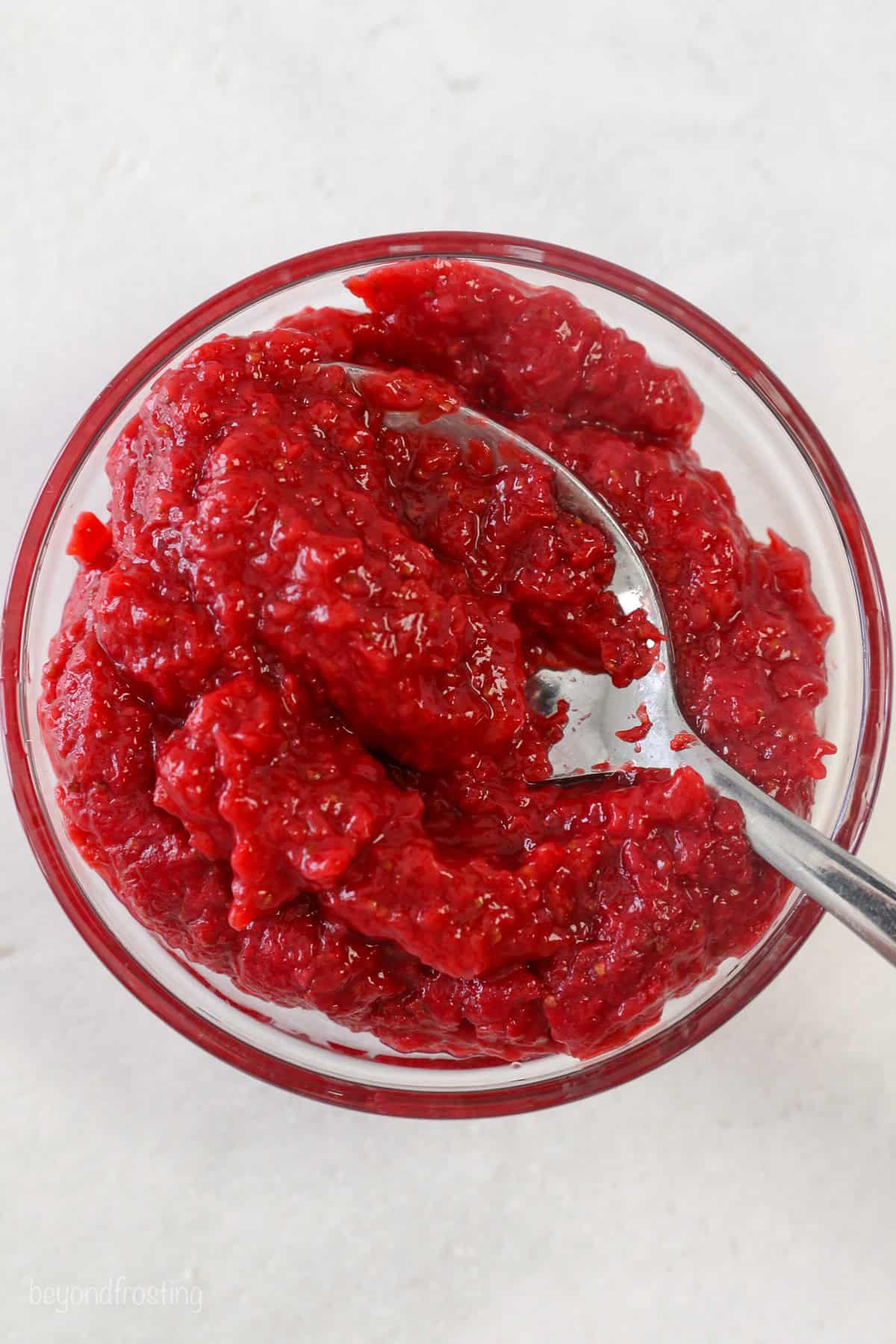 A spoonful of strawberry puree held over more puree in a bowl.