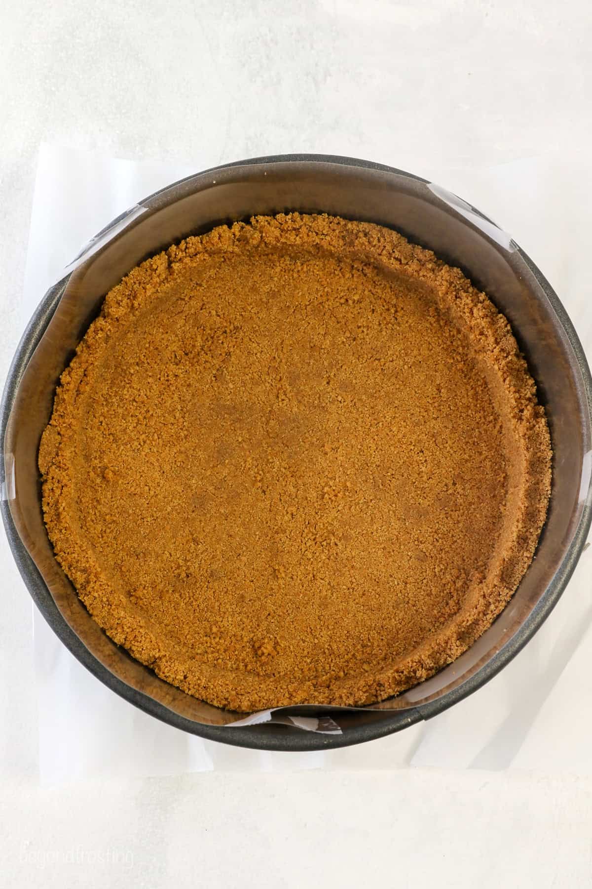 Graham cracker crust inside a springform pan.