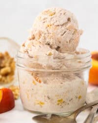 A small glass mason jar with scoops of peach ice cream