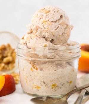 A small glass mason jar with scoops of peach ice cream