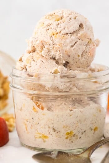 A small glass mason jar with scoops of peach ice cream