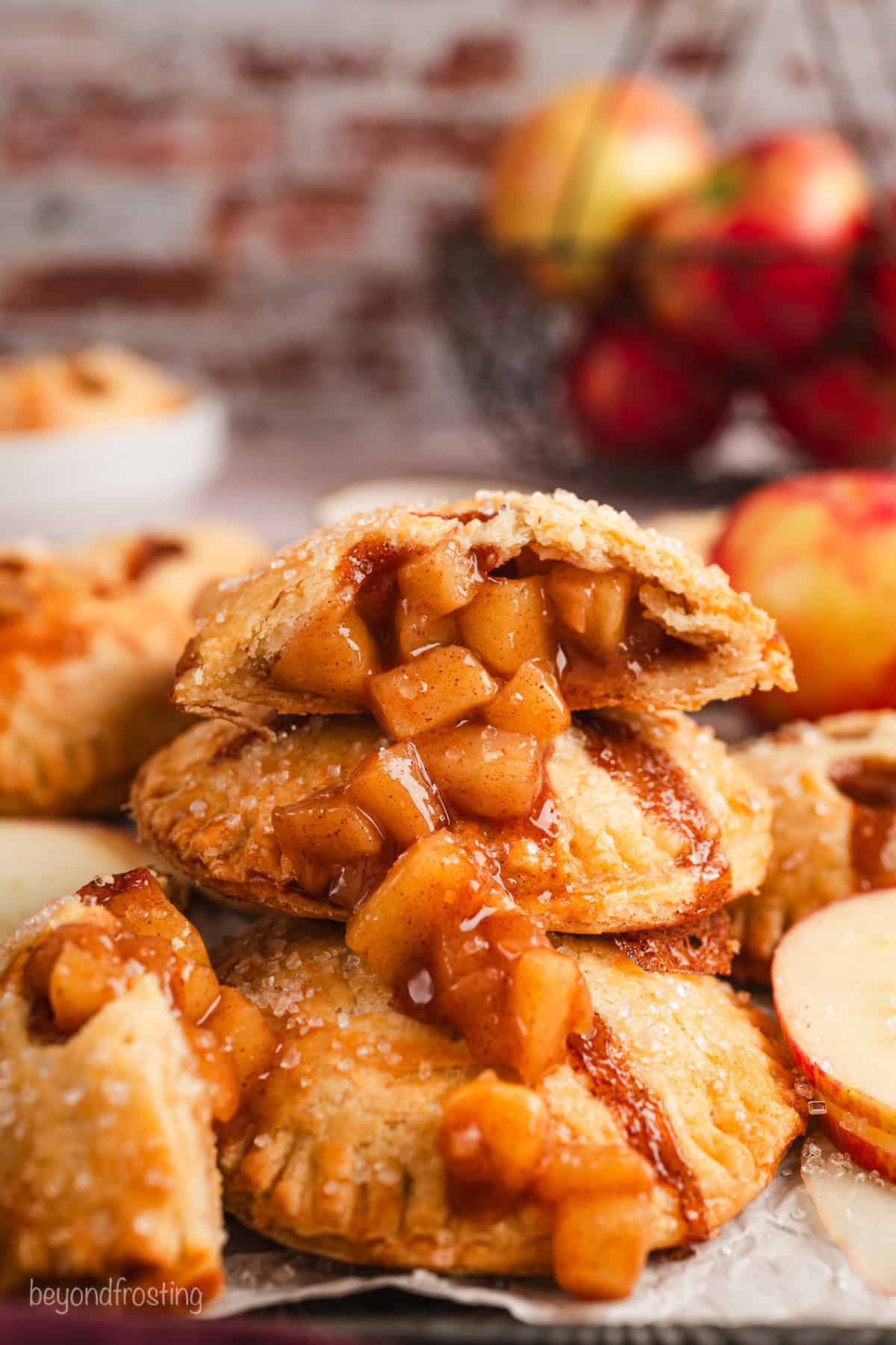 Side view of one half of an apple hand pie spilling apple filling over a stack of hand pies below.