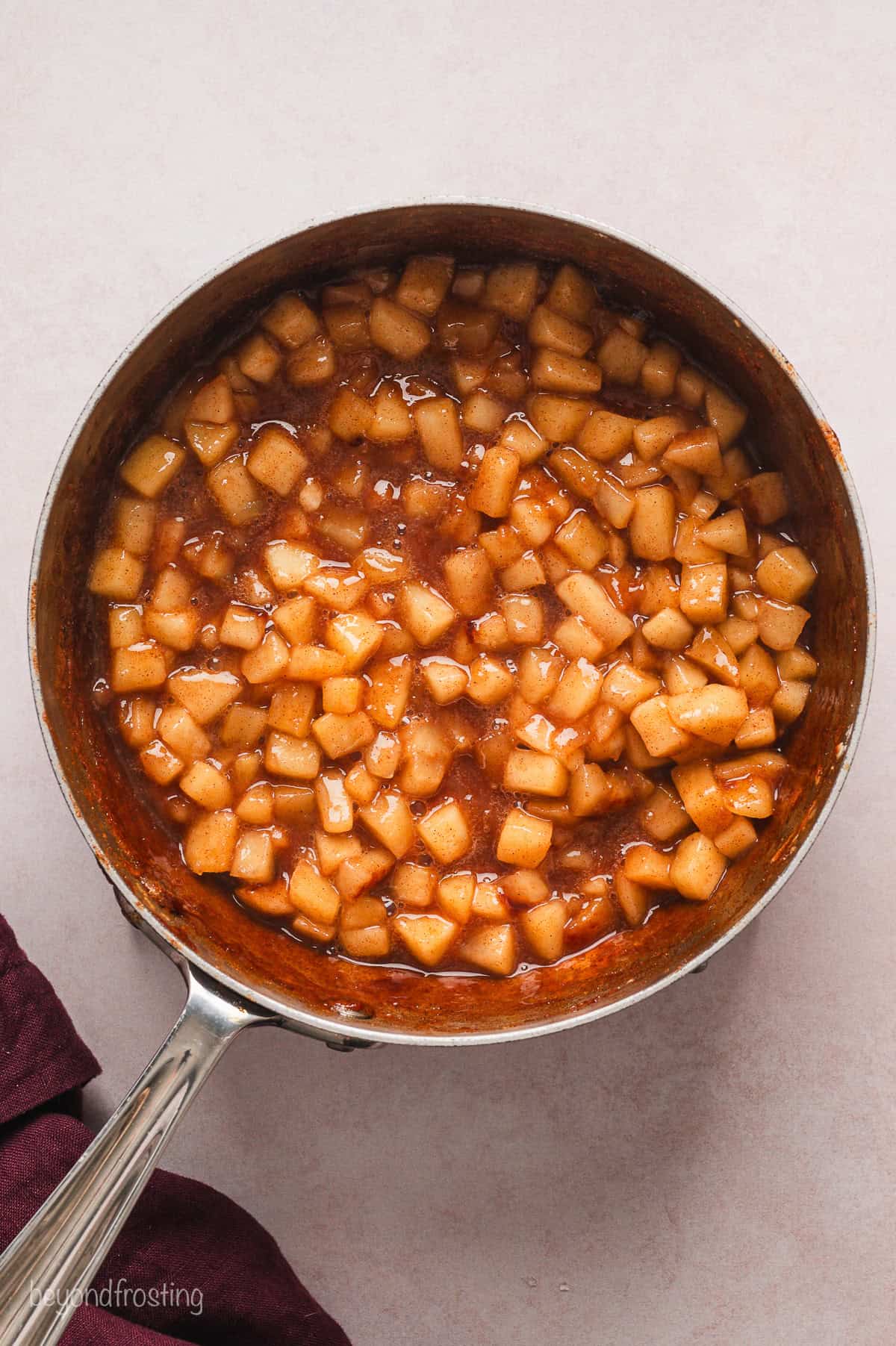 Cooked apple pie filling in a saucepan.