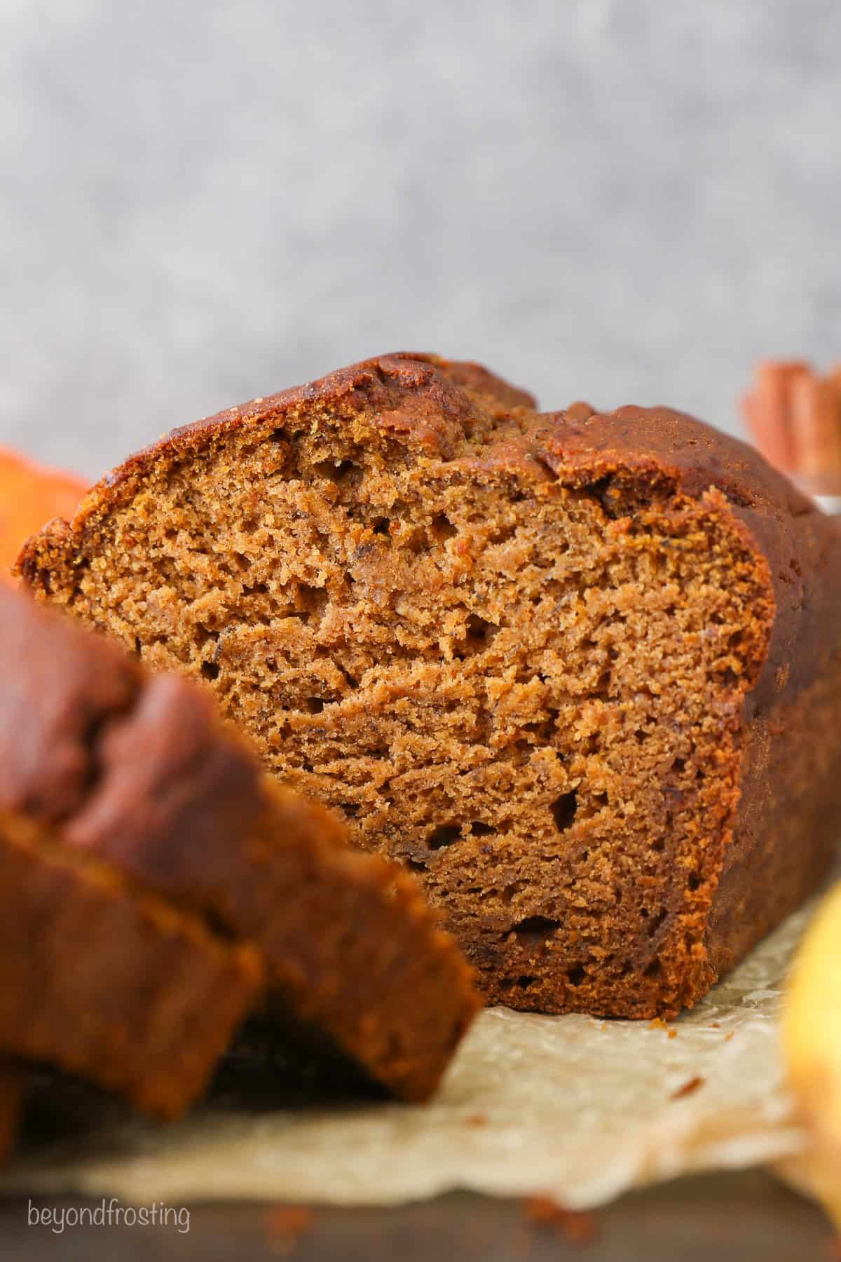 Front view of a loaf of pumpkin banana bread with slices cut from the end.