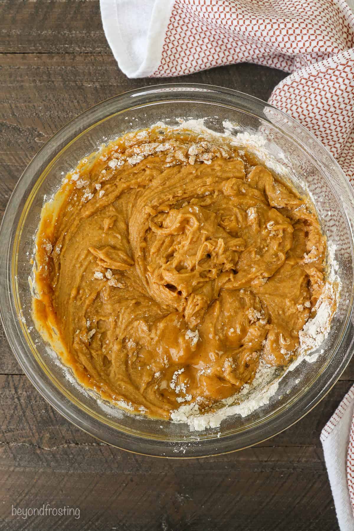 Wet and dry muffin batter ingredients coming together in a glass mixing bowl.