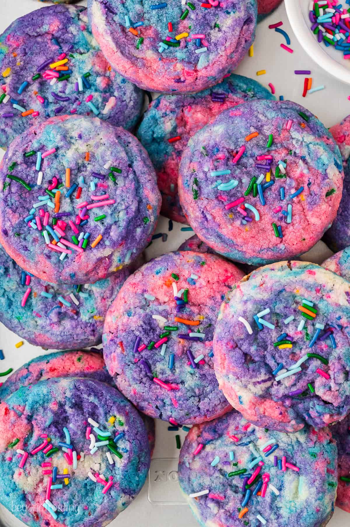 Overhead view of assorted unicorn cookies decorated with rainbow sprinkles.