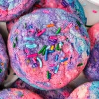 A close up of a tye dye cookie with pink, blue and purple with sprinkles made to look like Unicorn Poop
