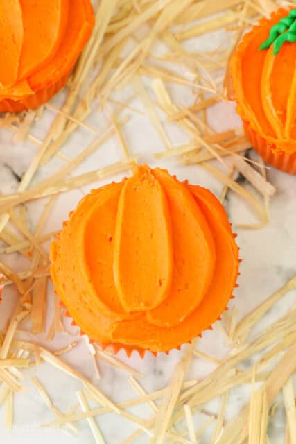 A final process shot for decorating pumpkin themed cupcakes for Halloween using orange buttercream