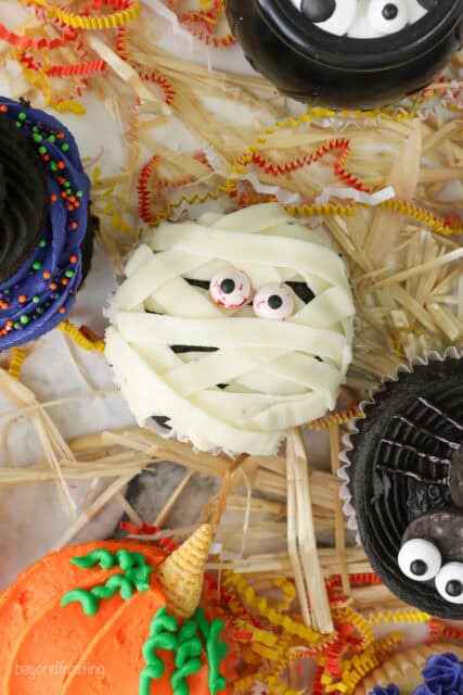 A close up of a cupcake decorated to look like a mummy with buttercream and candy eyes