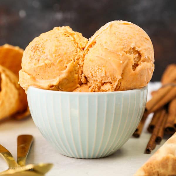 Two scoops of sweet potato ice cream in a light green bowl with 2 gold spoons next to it