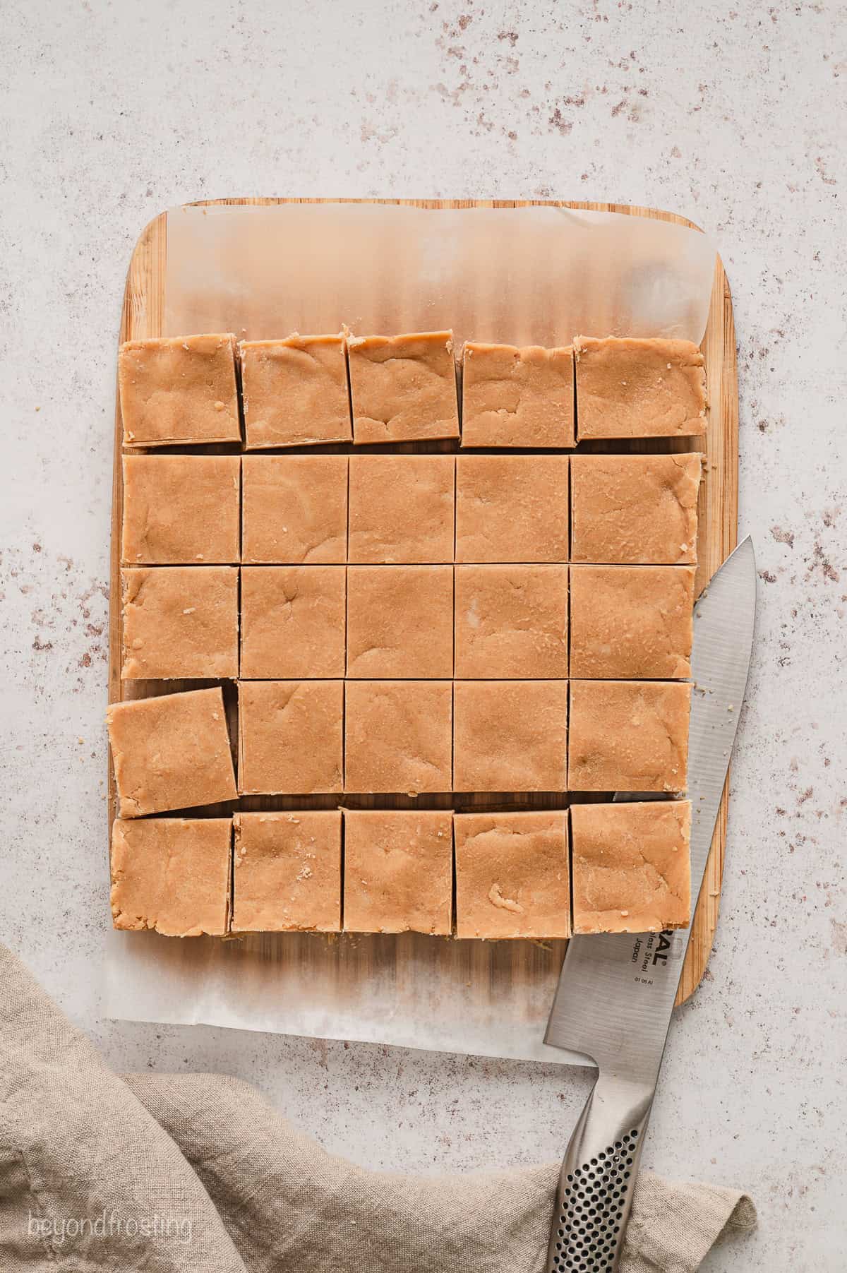 Overhead view of peanut butter fudge cut into squares on a large piece of parchment paper.