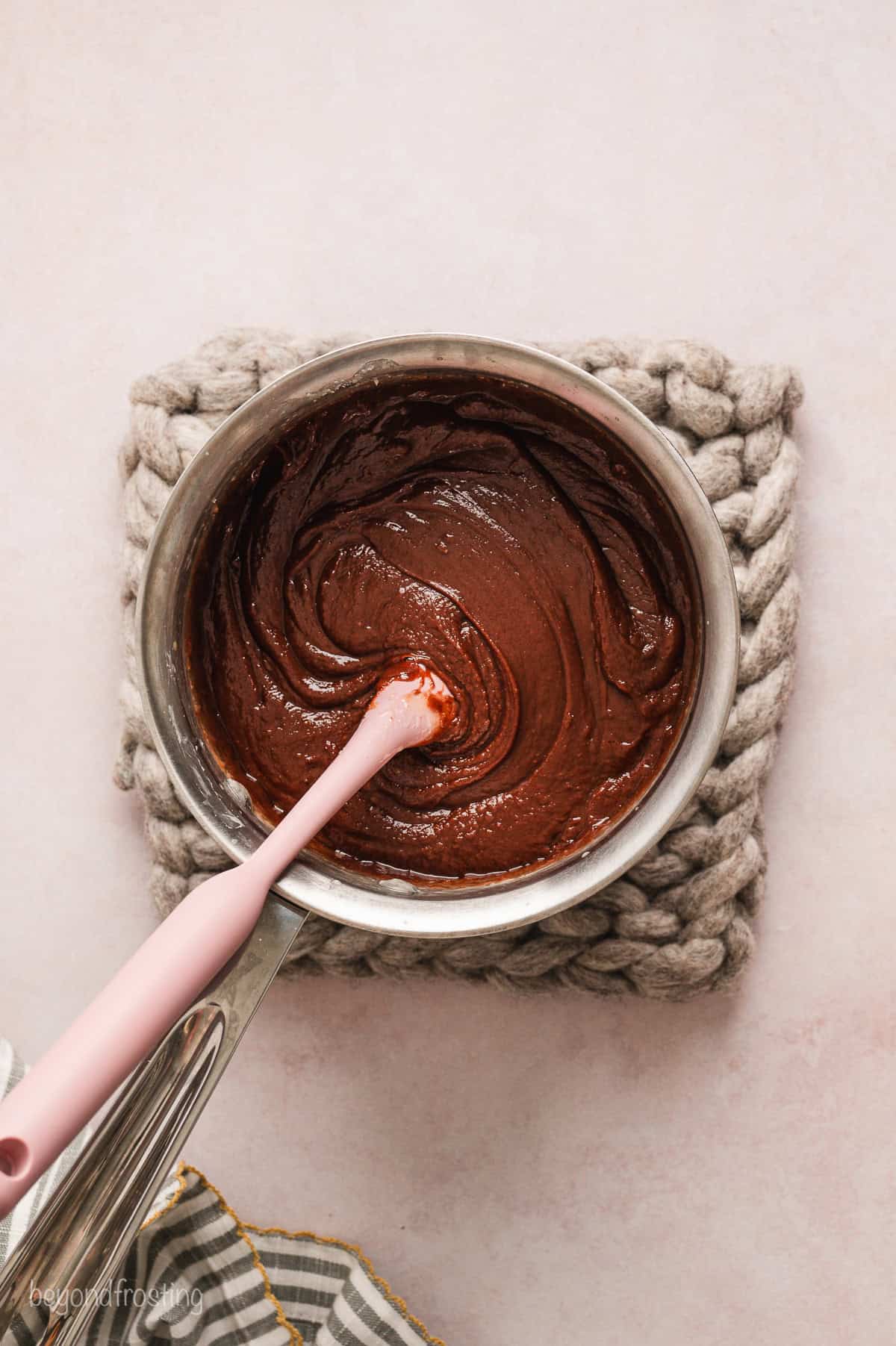 Fudge mixture in a saucepan with a rubber spatula.