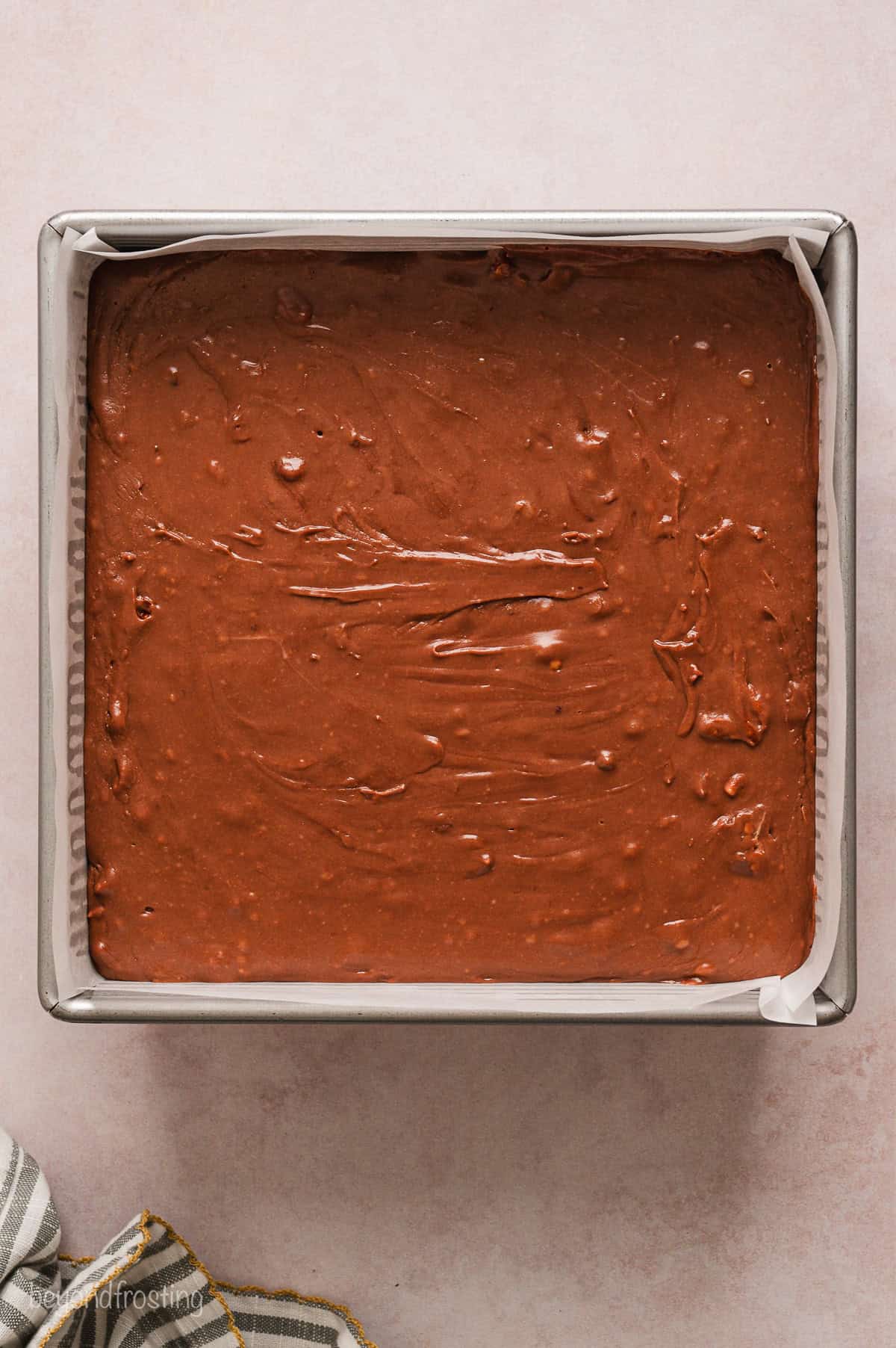 Fudge mixture in a lined square baking pan.