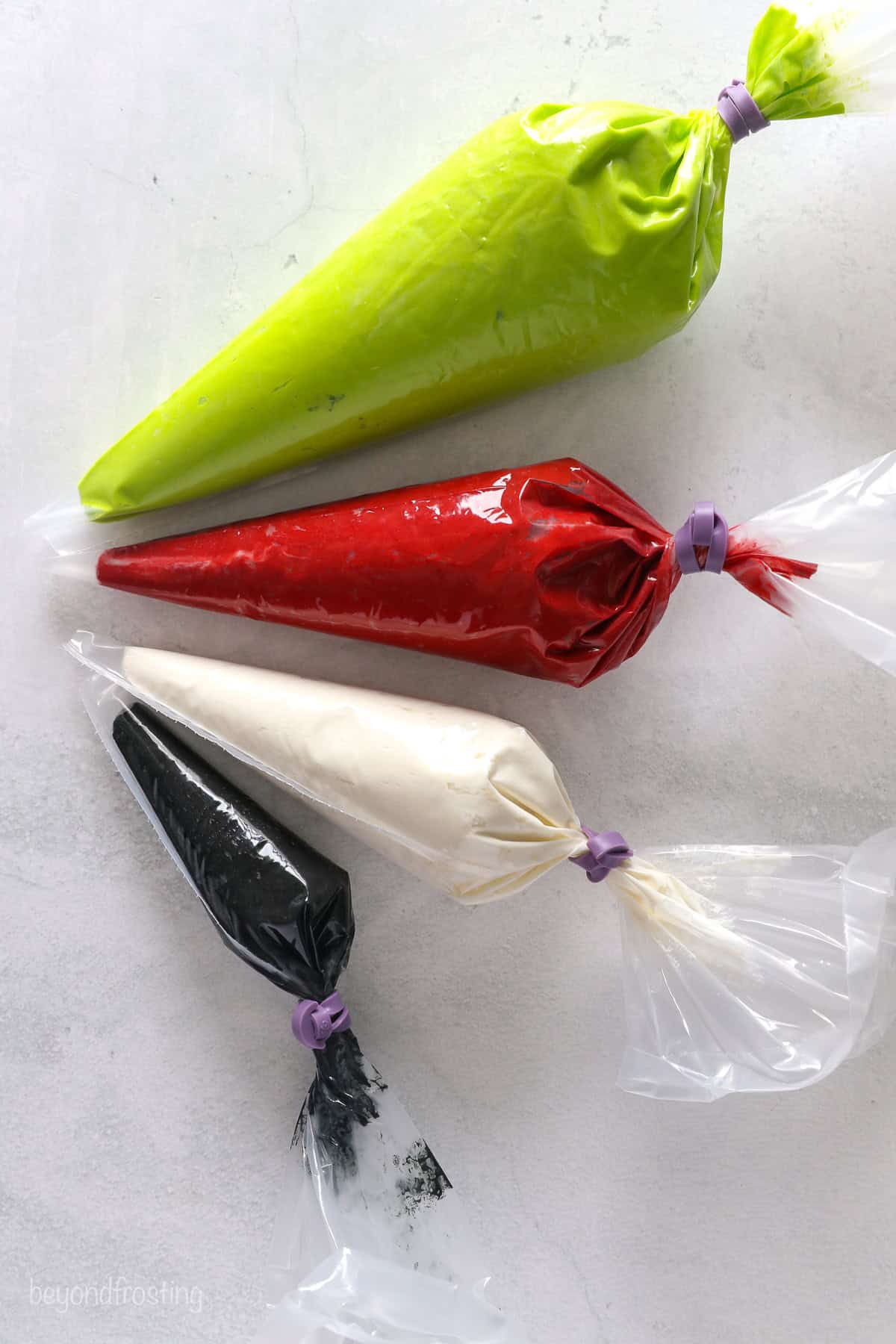 4 piping bags filled with frosting including bright green, red, white and black