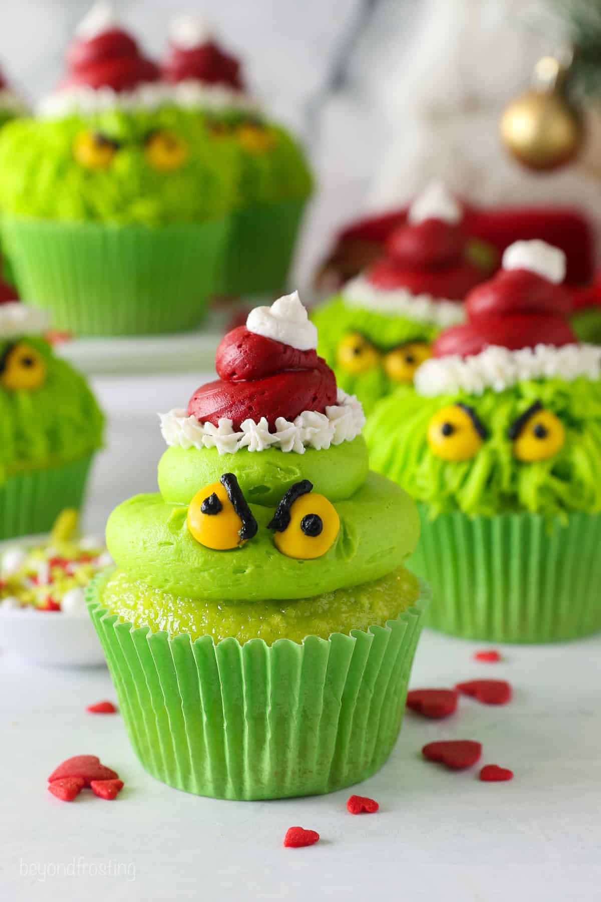 A finished Grinch cupcake with more decorated cupcakes in the background.