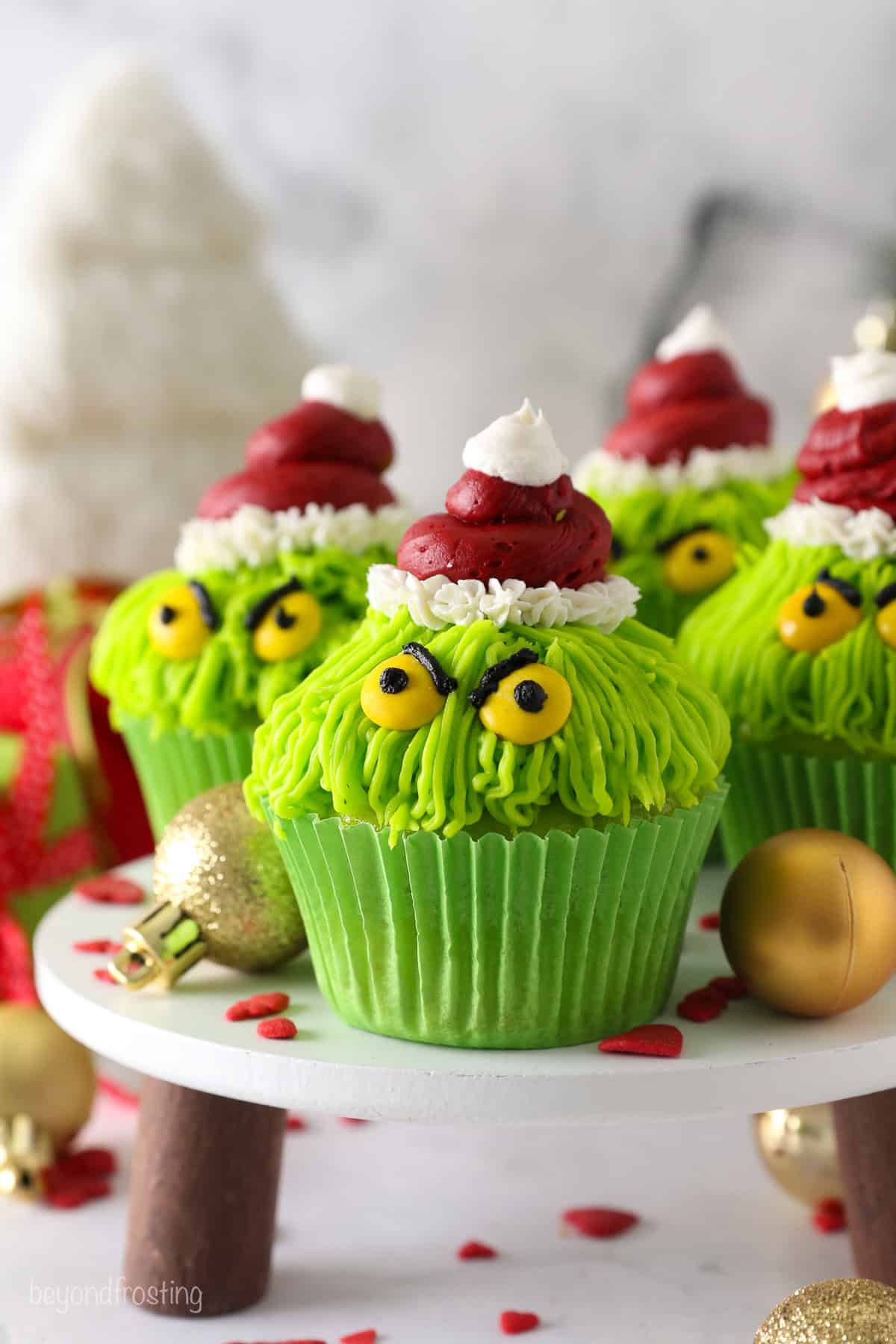 Grinch cupcakes on a raised cake stand.