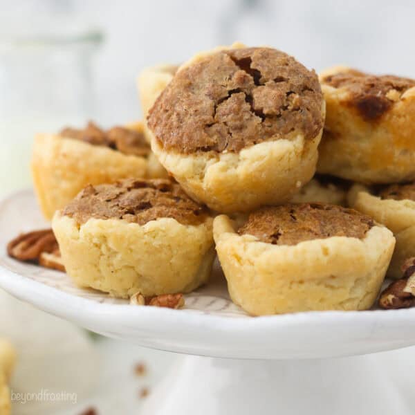 Mini pecan tarts stacked on a white cake stand.