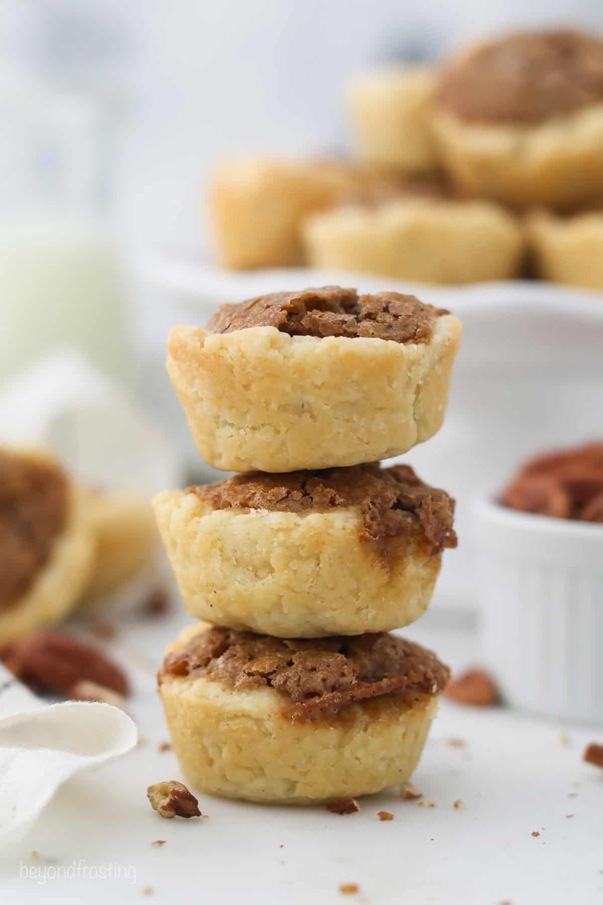 Three mini pecan pie tarts stacked on top of one another.