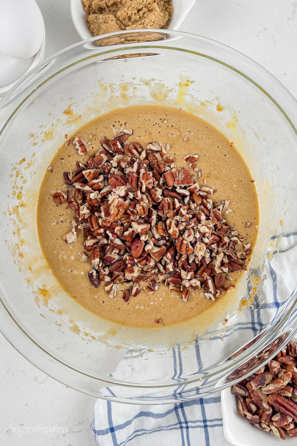 Pecans added to the tart filling in a glass bowl.