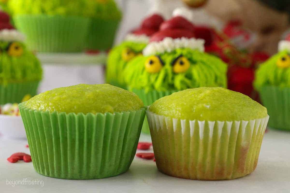 Two green cupcakes side by side, one baked in a bright green cupcake liner and the other in a regular white cupcake liner.