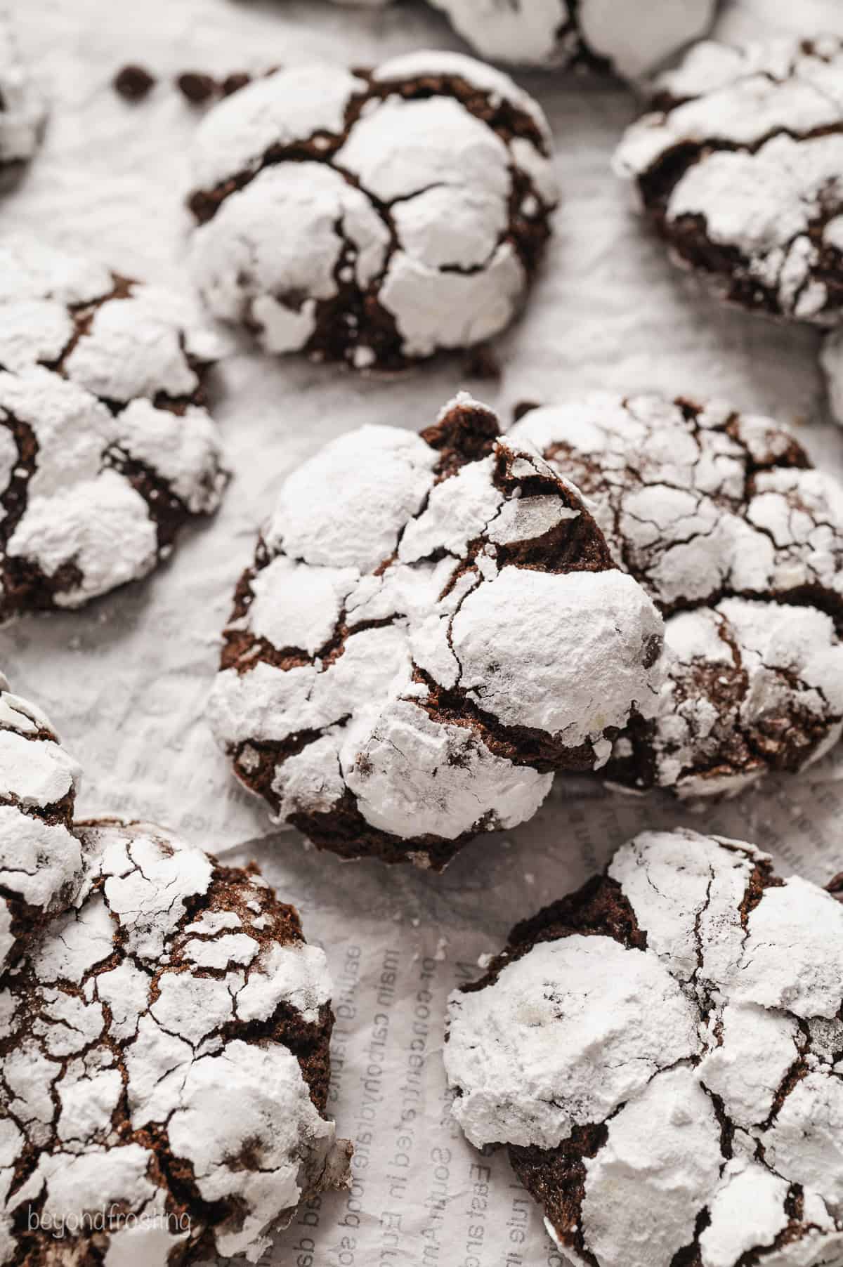 Overhead view of assorted chocolate crinkle cookies on a sheet of parchment paper.