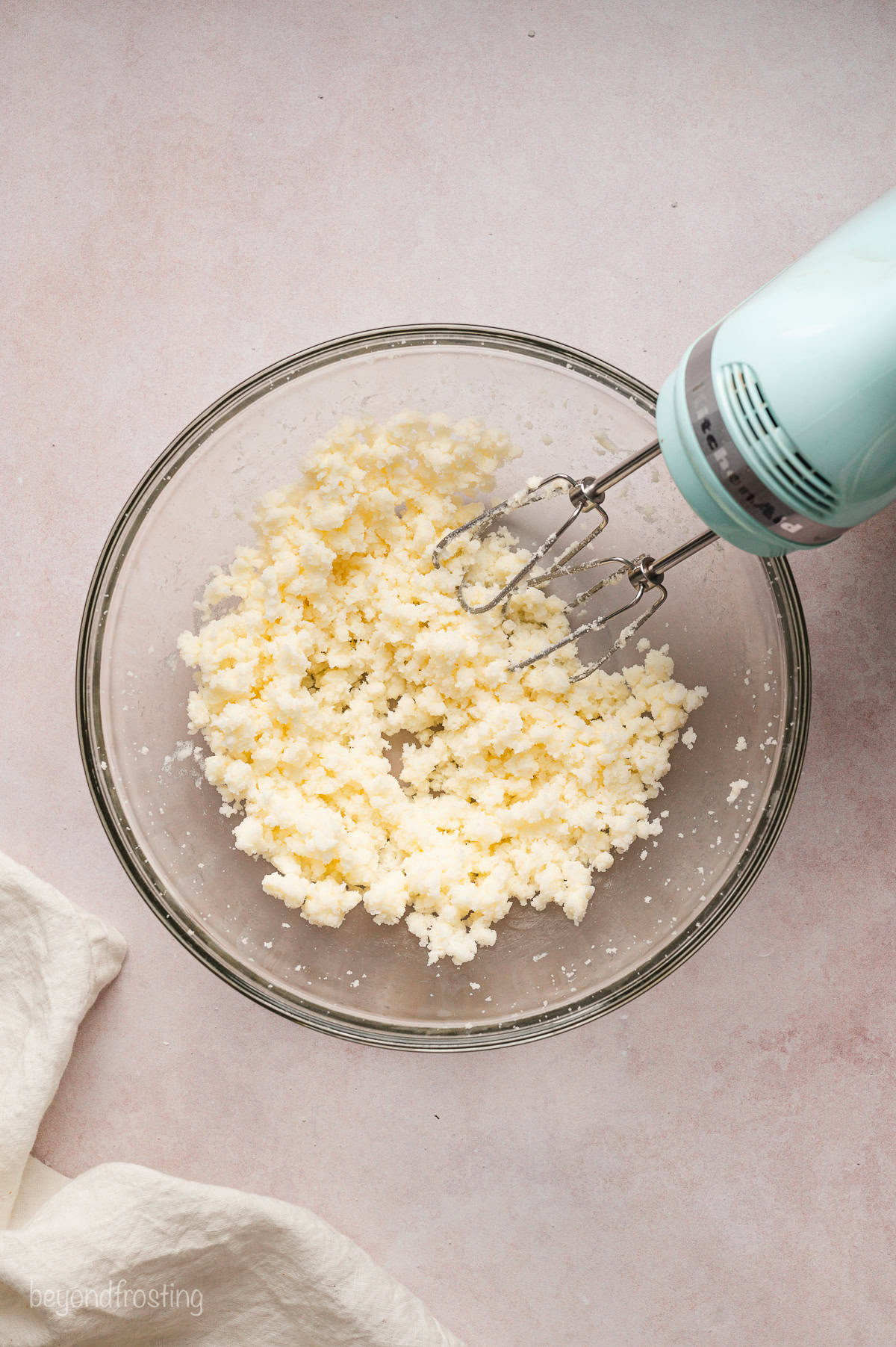 A hand mixer resting in a bowl of beaten butter.