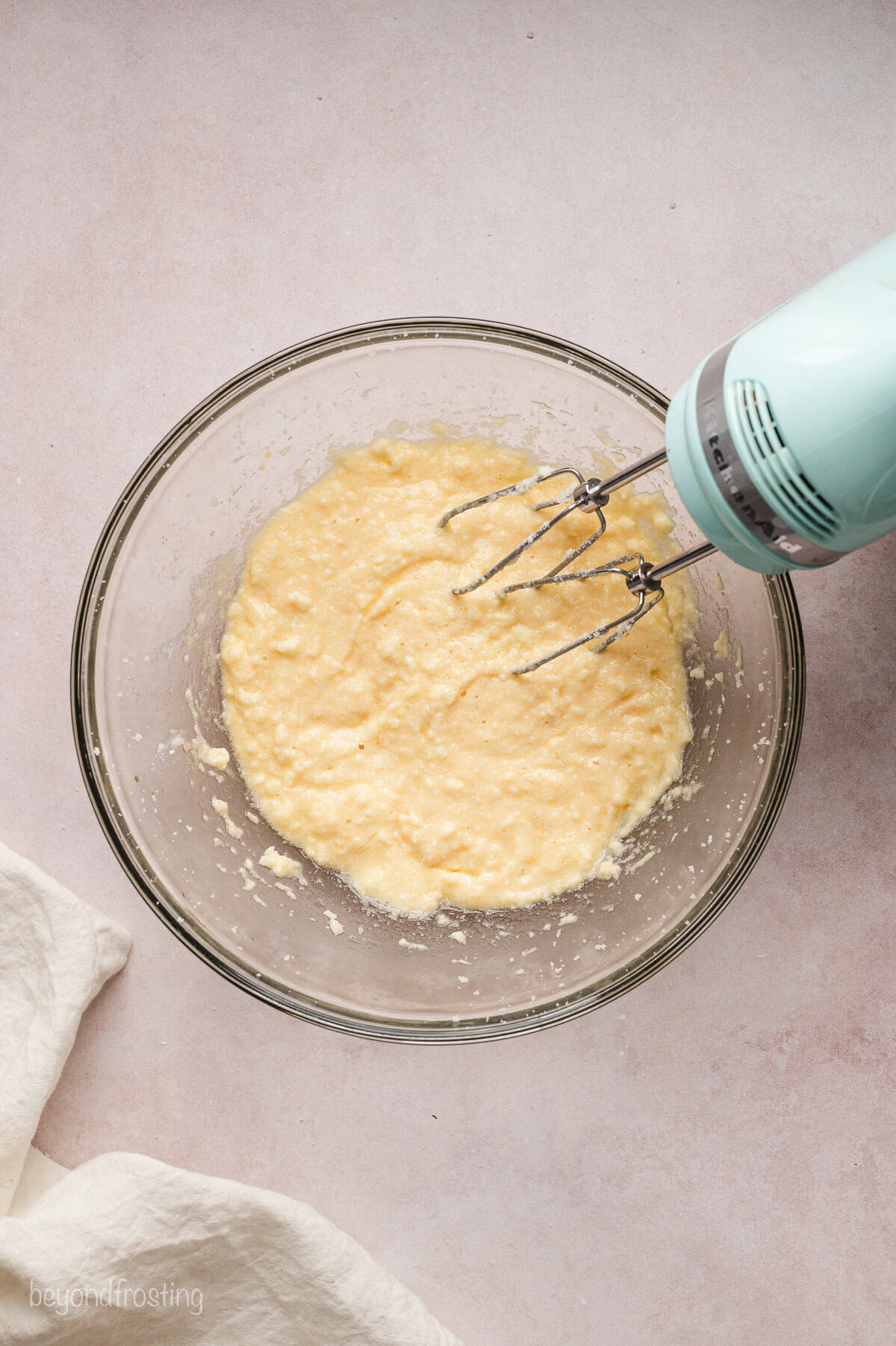 A hand mixer resting in a bowl of cookie dough mixture.