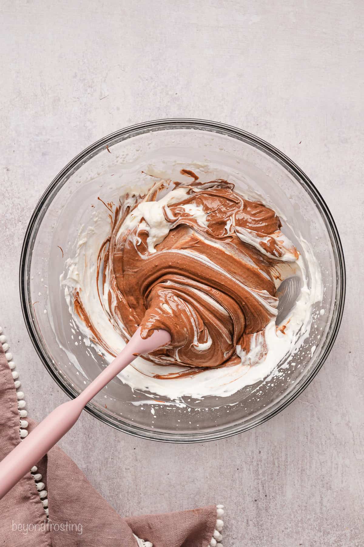 Folding the chocolate into whipped cream in a glass bowl to make French silk pie filling.