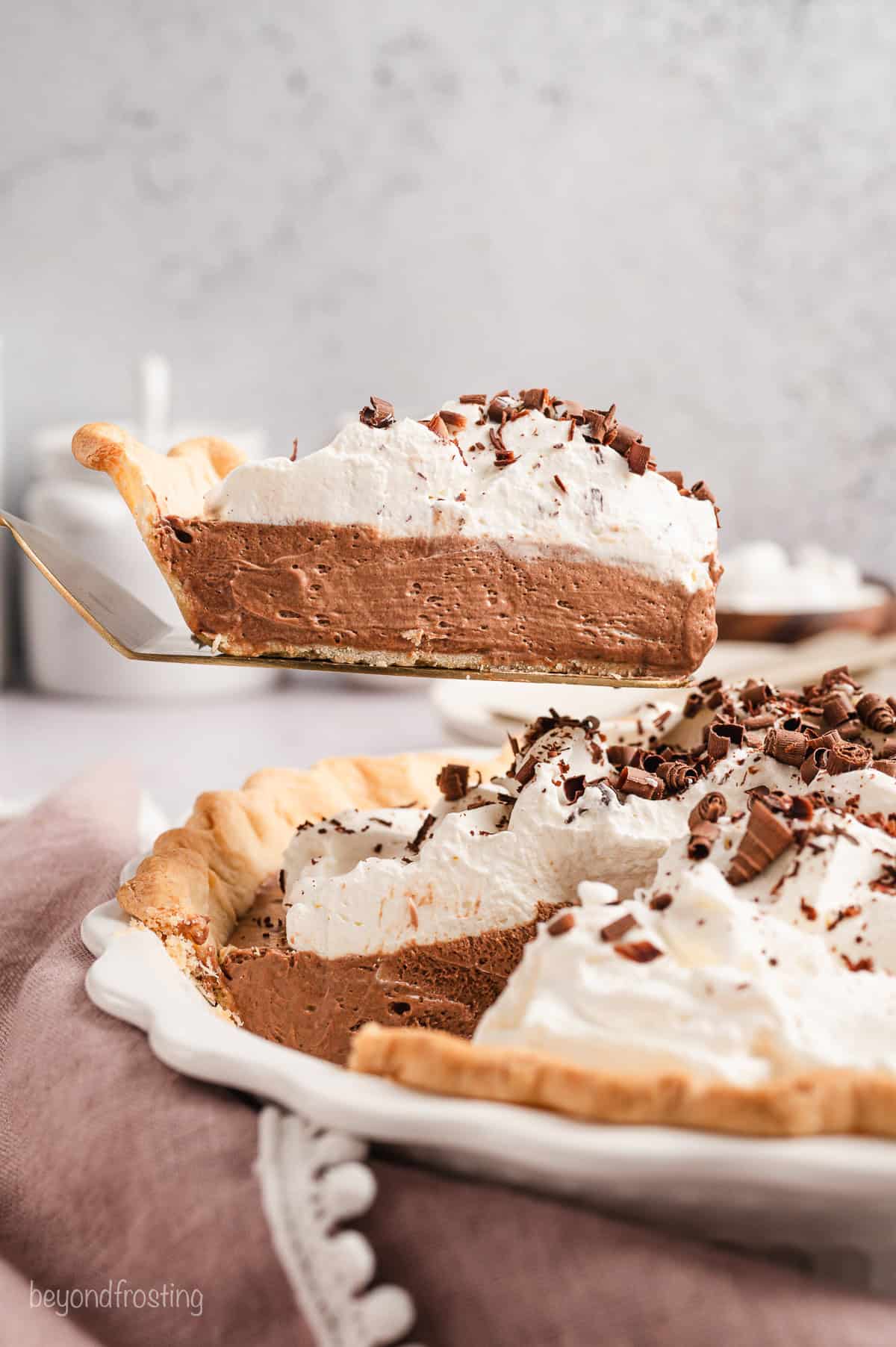 A slice of French silk pie being lifted from a pie plate with a cake server.