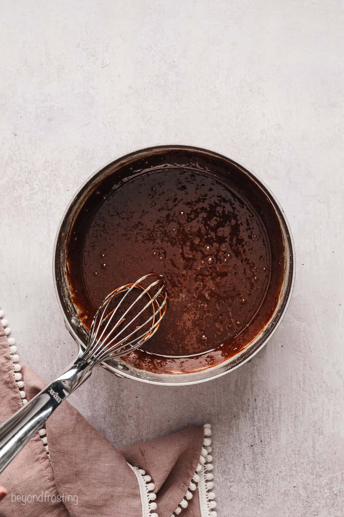 Melted chocolate in a saucepan with a whisk.