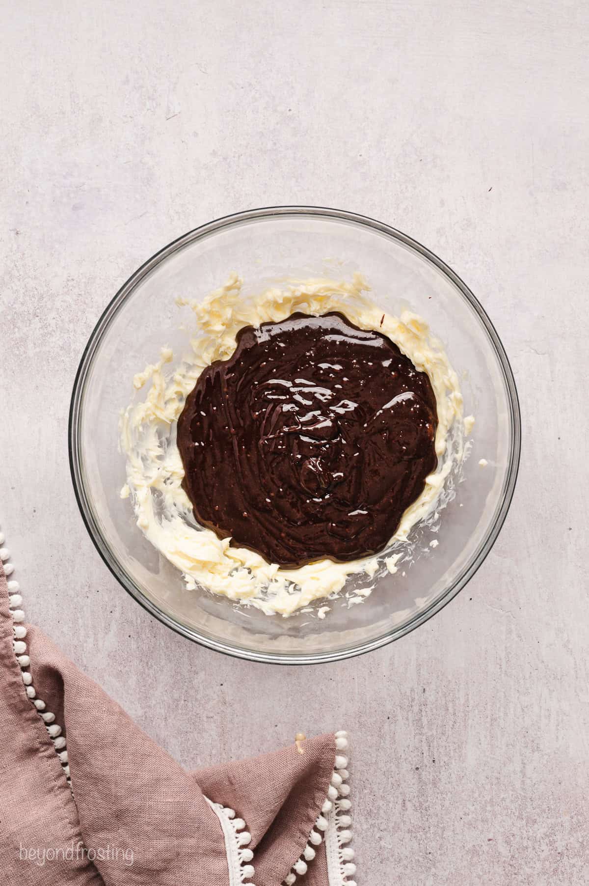 Melted chocolate added to a bowl of whipped butter.