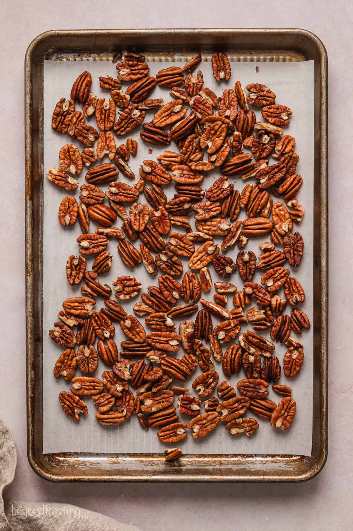 Toasted pecans on a parchment-lined baking sheet.