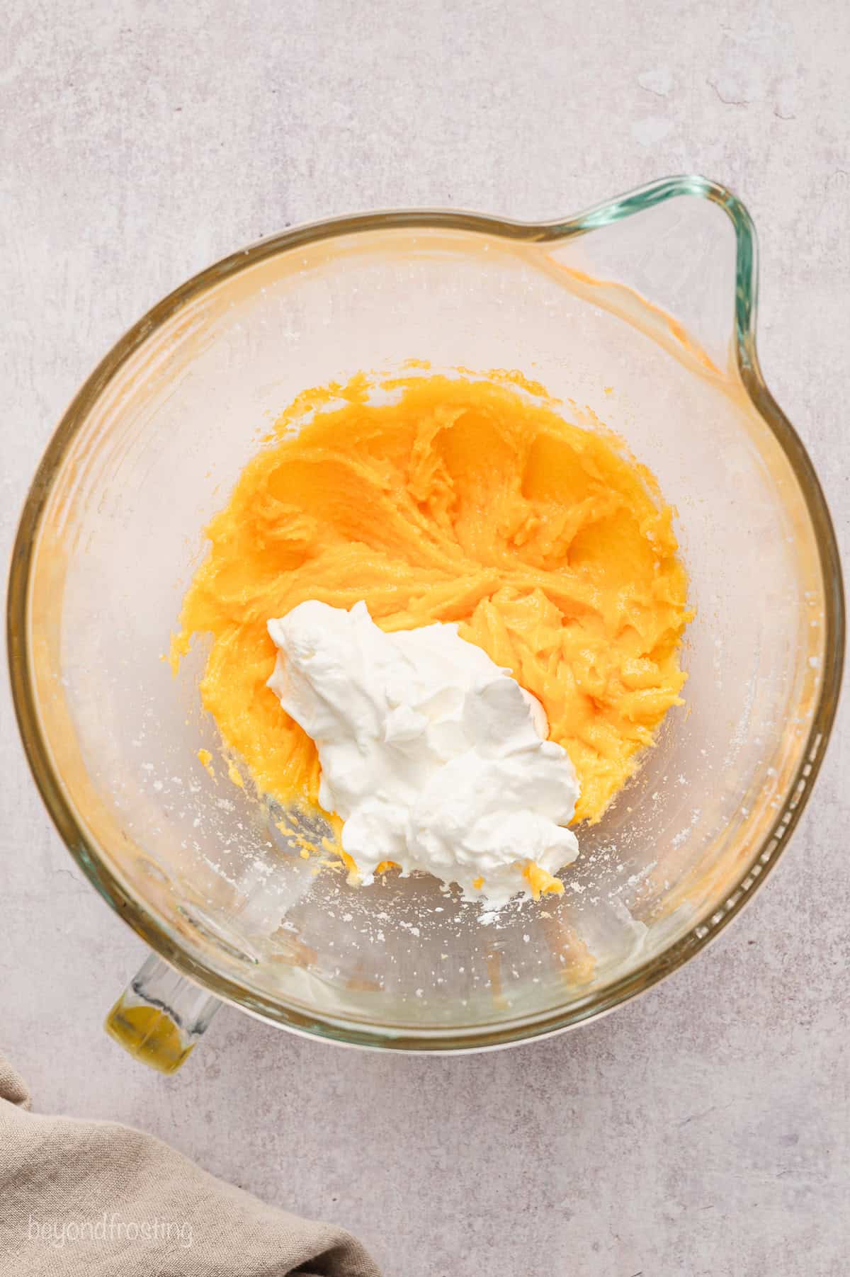 Sour cream added to beaten egg yolks, sugar, butter, and shortening in a mixing bowl.