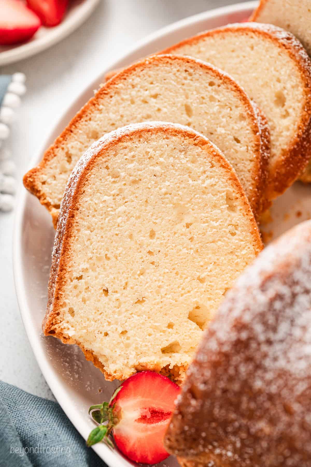 Close up of a cream cheese pound cake cut into slices on a plate.