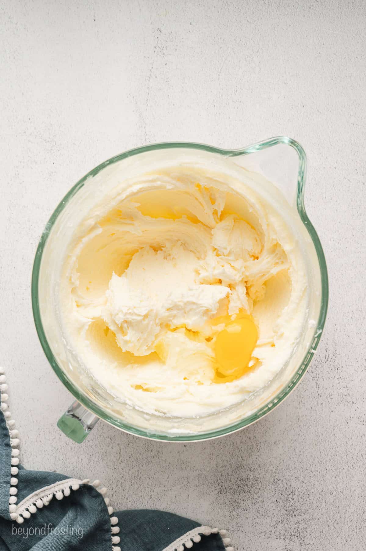 Eggs added to beaten butter, cream cheese, and sugar in a mixing bowl.