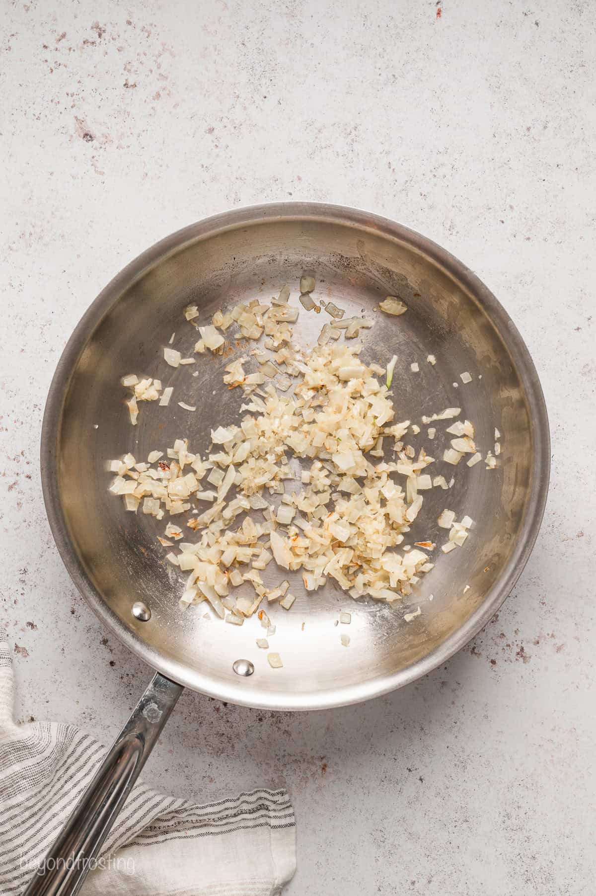 Diced onions and garlic sautéing in a skillet with butter.