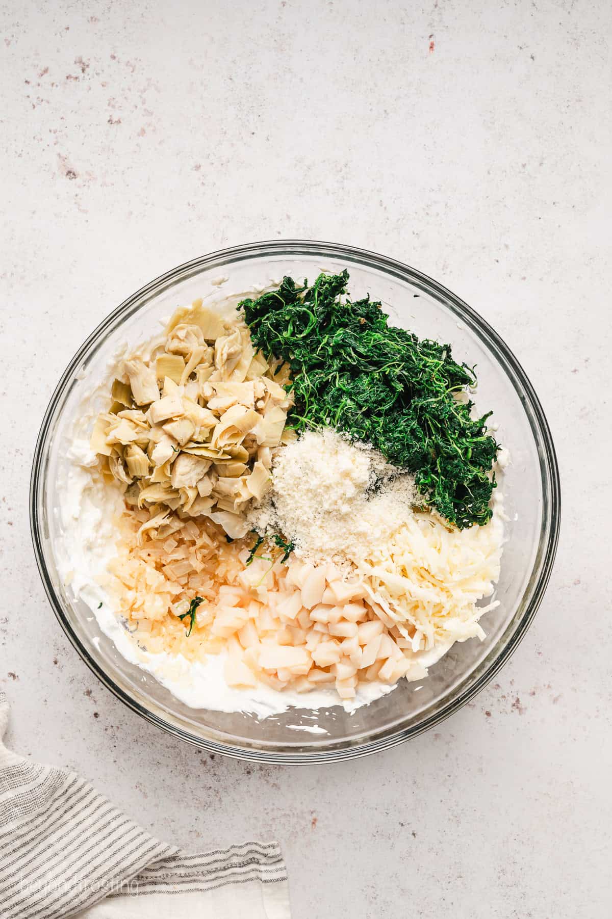 Spinach artichoke ingredients combined in a glass bowl.