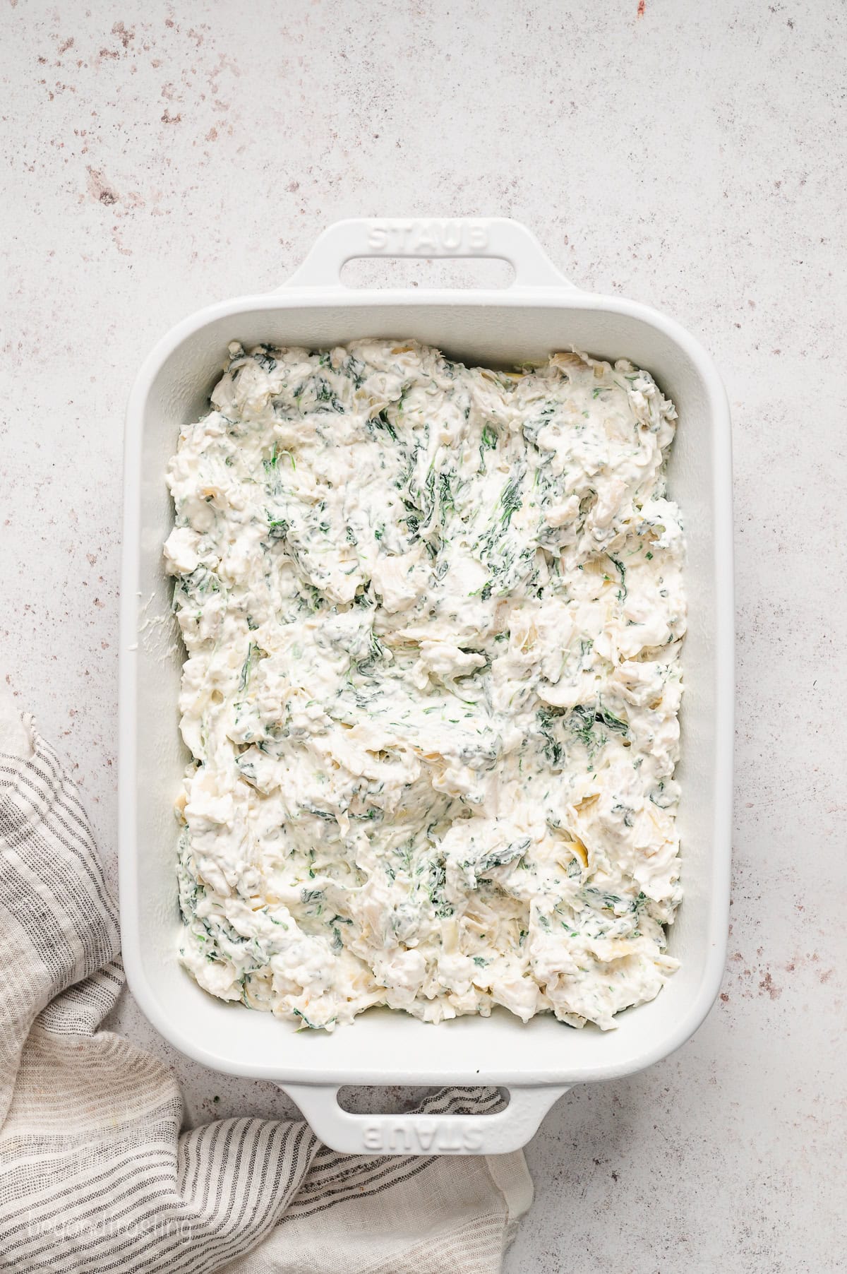 Spinach artichoke dip inside a ceramic baking dish.